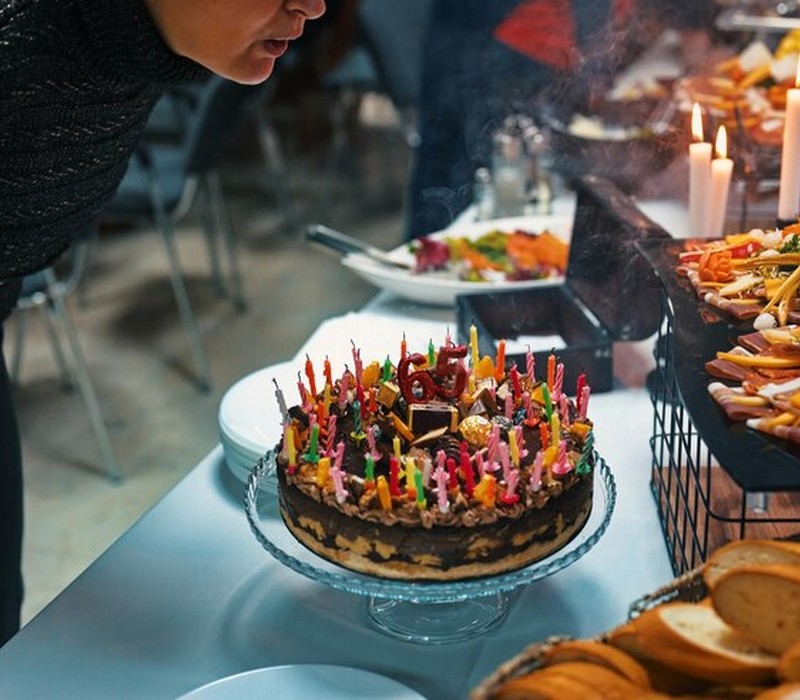 senior woman blowing birthday cake with candles 1048944 26574589